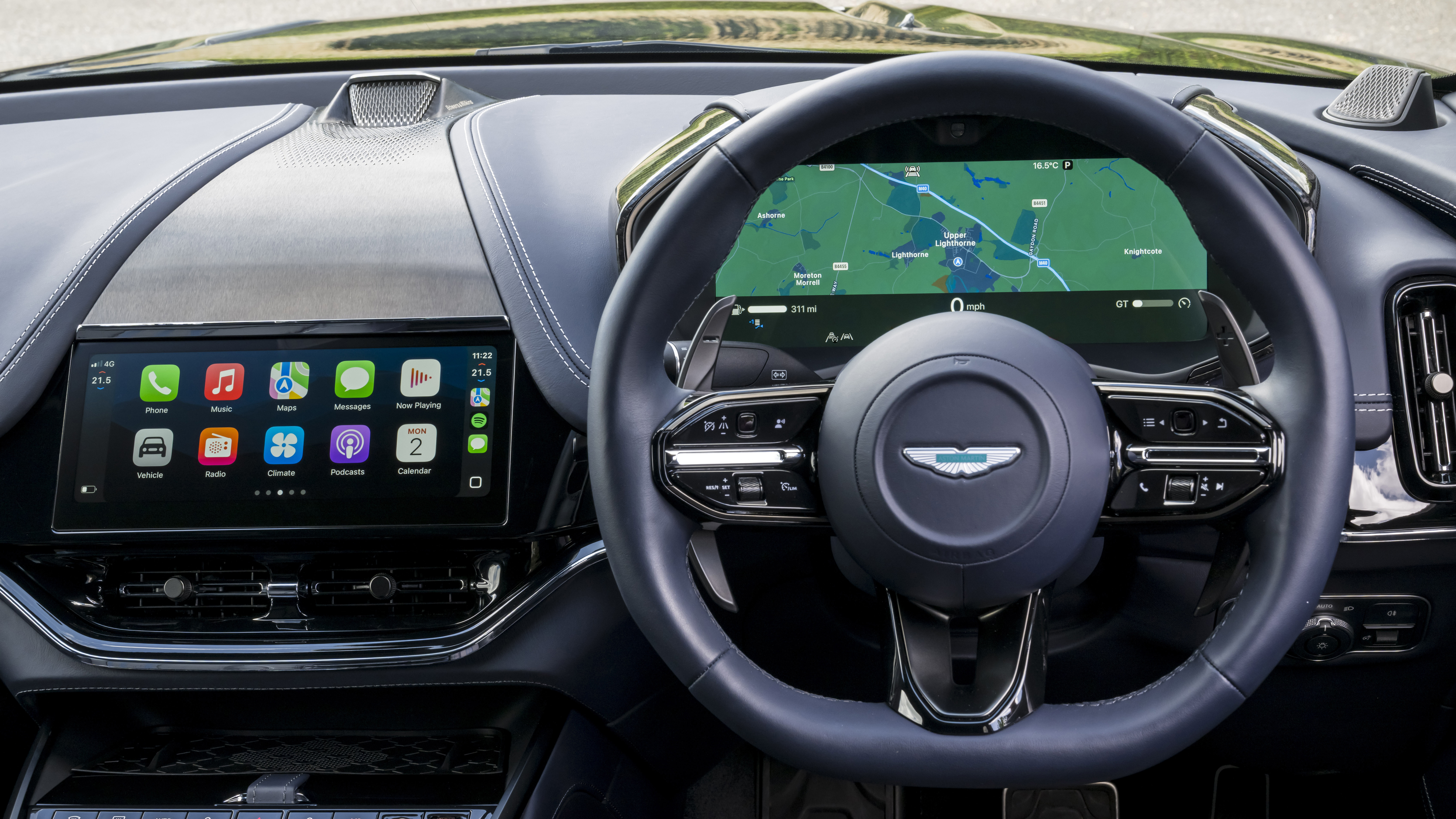 A car's steering wheel and dashboard showing Apple CarPlay Ultra