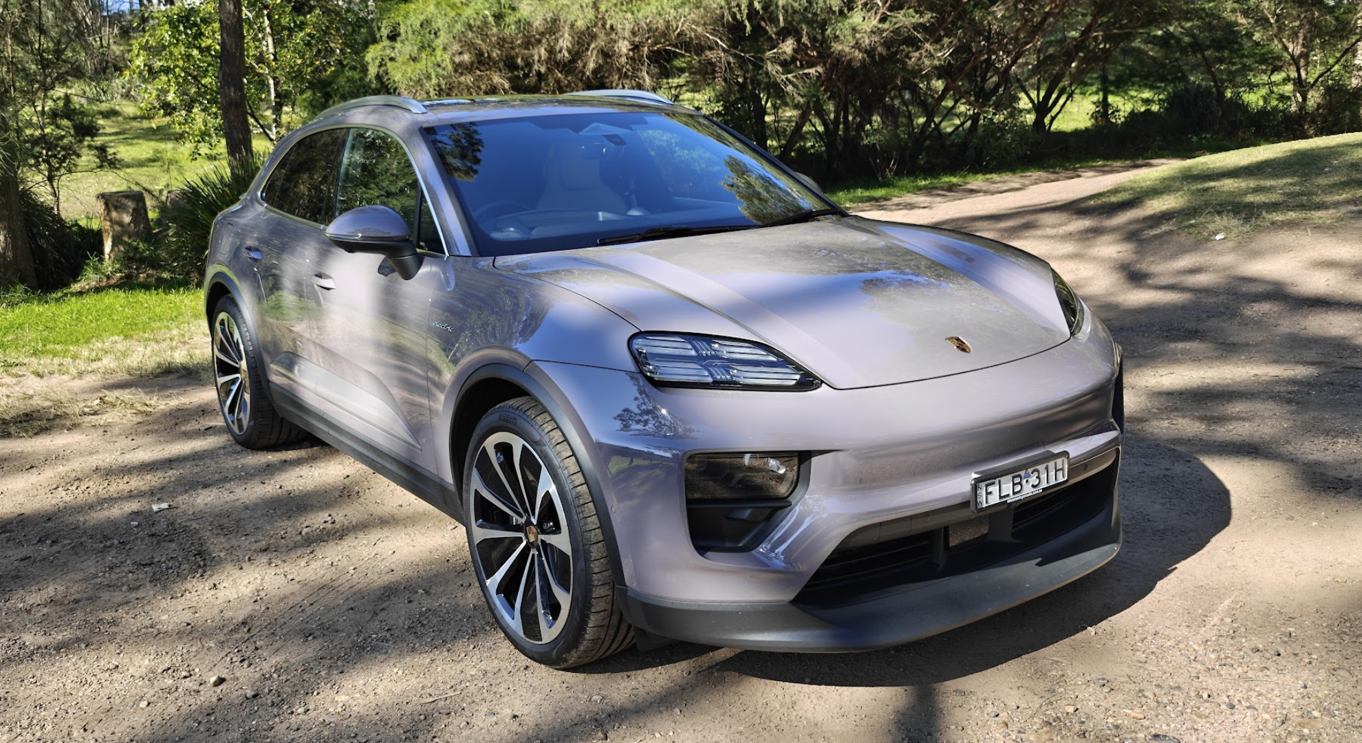 A Porsche Macan EV parked on dirt