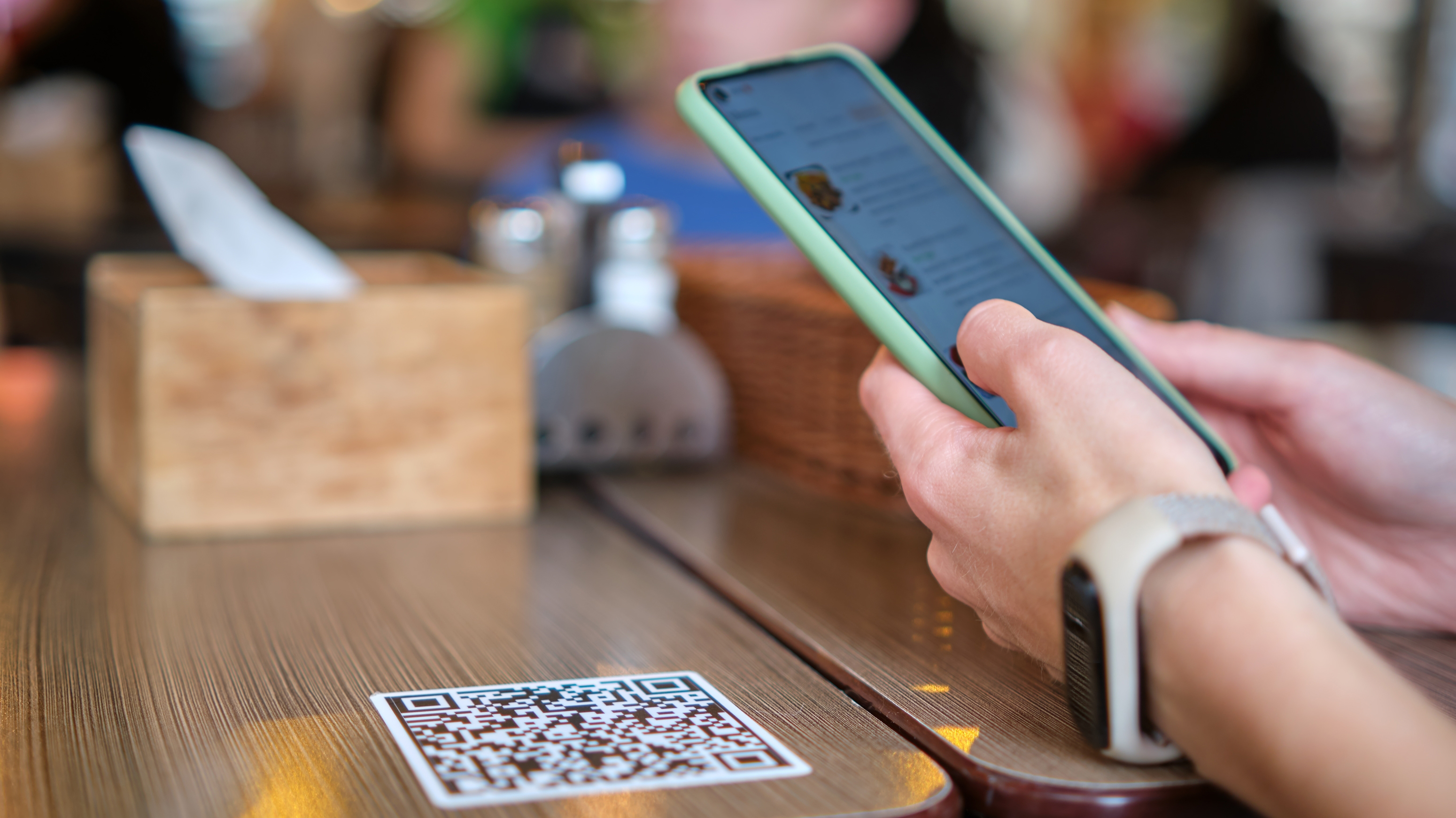 Closeup of a hand ordering a meal in restaurant while scanning a QR code with a mobile phone