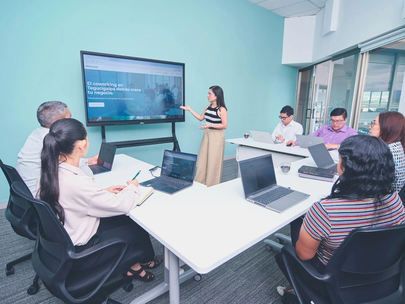 A diverse group in a collaborative meeting using a digital display in a modern office.